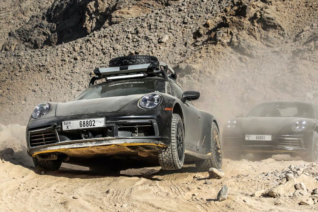 zwei-porsche-911-dakar-fahren-durch-wuestenlandschaft