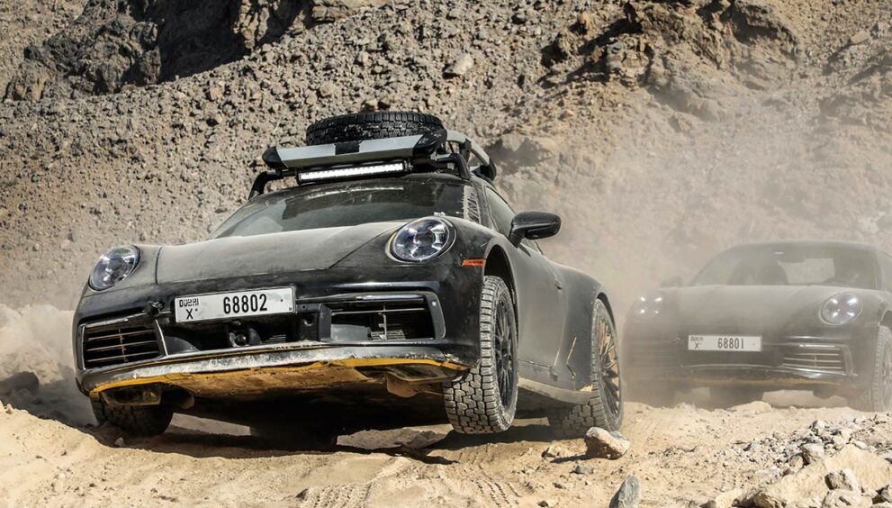 zwei-porsche-911-dakar-fahren-durch-wuestenlandschaft