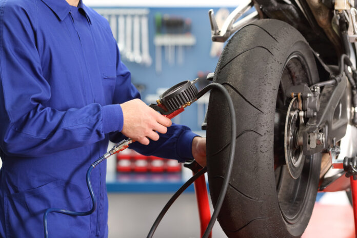 mann-in-blau-pumpt-reifen-motorrad-auf